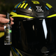 Hand holding Xzone helmet detaller spray next to a glossy motorcycle helmet visor.